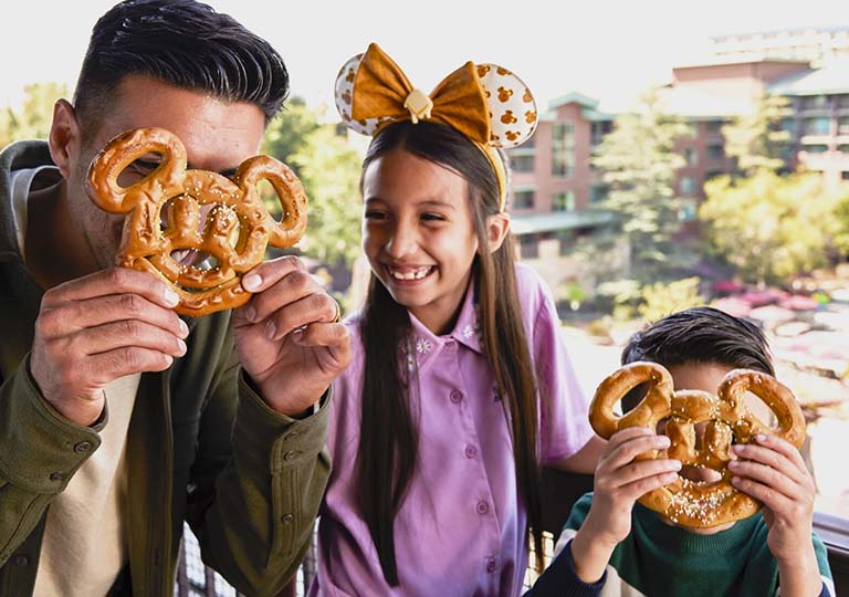 Dad and kids holding a Mickey Mouse pretzel