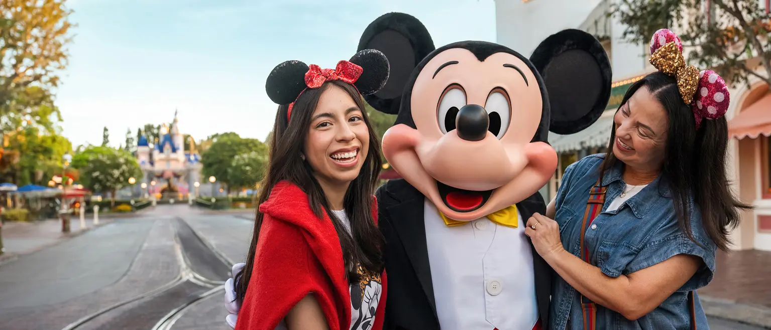 Two women standing with Mickey Mouse.