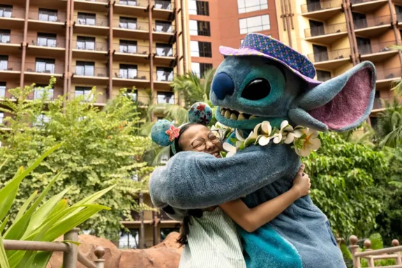 Stitch hugging to Disney fan wearing Mickey Mouse ears at Aulani, A Disney Resort & Spa in Hawaiʻi.