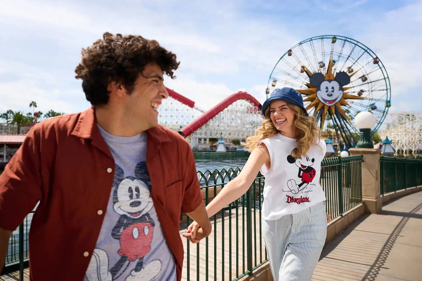 Laughing couple wearing Mickey t-shirts along the Pixar Pier boardwalk at Disney California Adventure.
