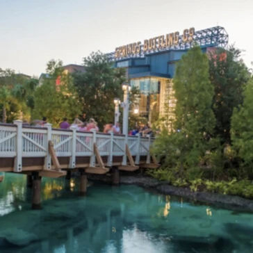 Guests walking over a bridge to Springs Bottling Co at Disney Springs.
