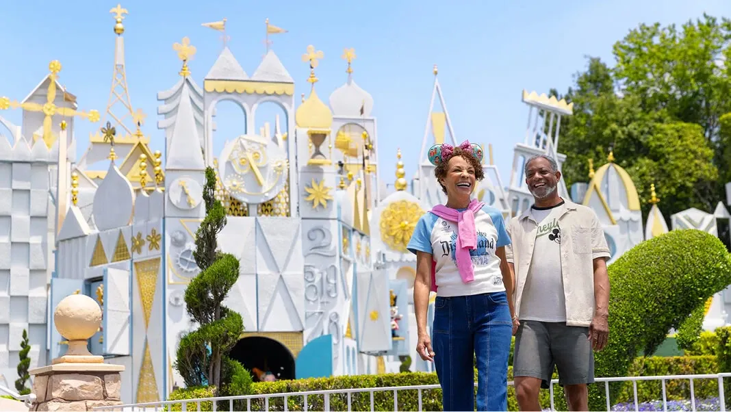 Couple smiling at the "It’s A Small World" attraction at Disneyland.