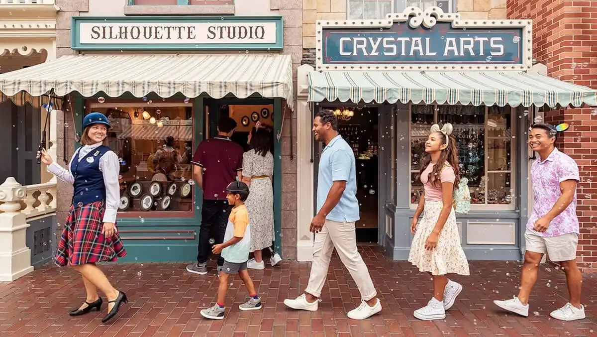 Family following a Disneyland cast member along Silhouette Studio and Crystal Arts on Main Street, U.S.A.