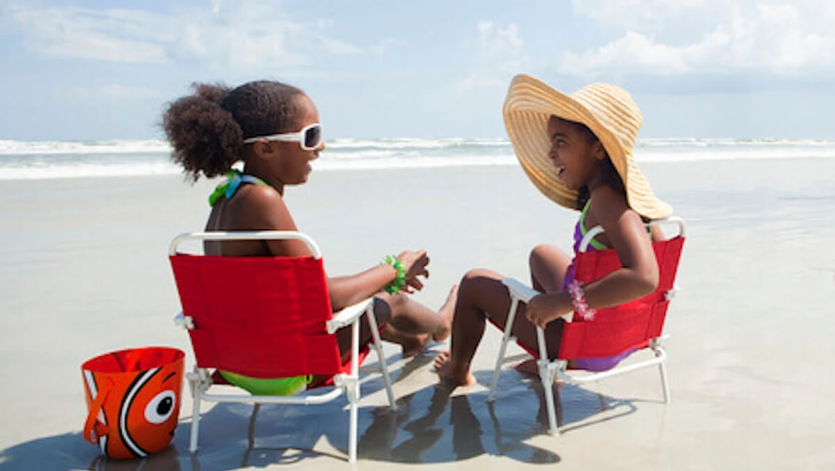 Two girls laughing at the beach with a Nemo bucket.