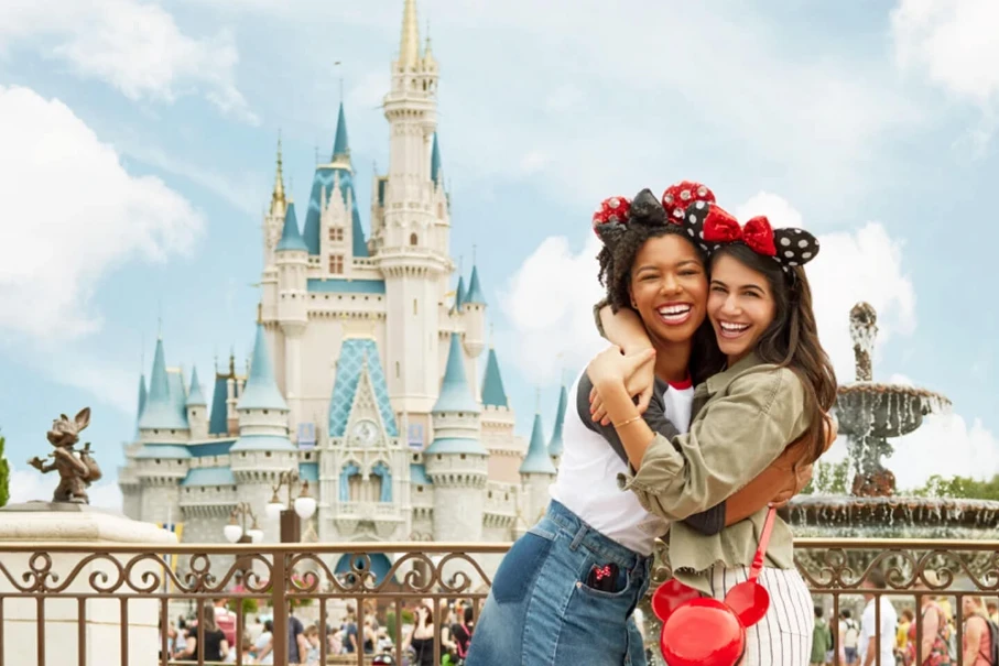 Friends hugging with Mickey Mouse ears in front of Cinderella Castle at Magic Kingdom.