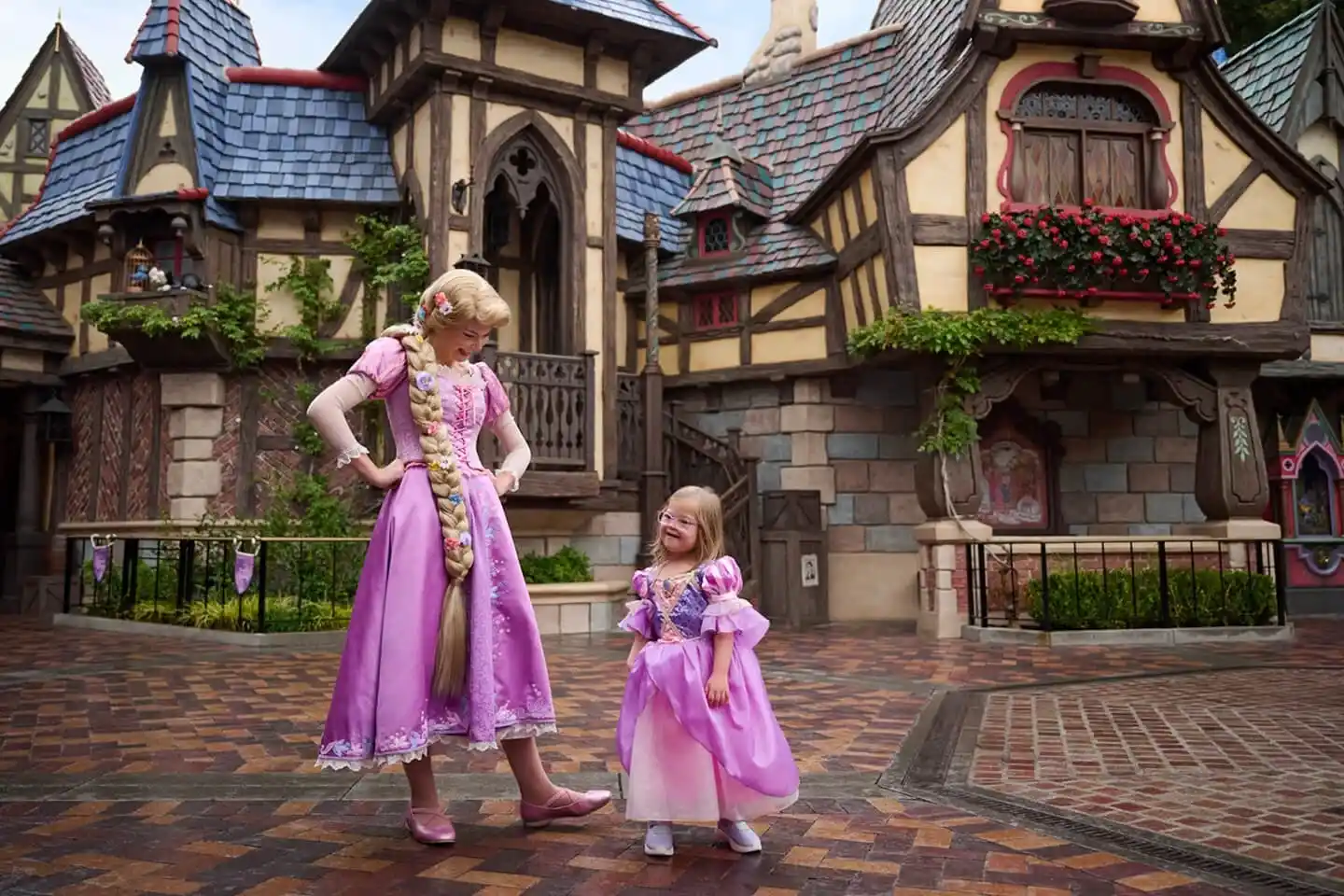 Rapunzel and toddler wearing matching dresses at Fantasy Faire in Disneyland Park.