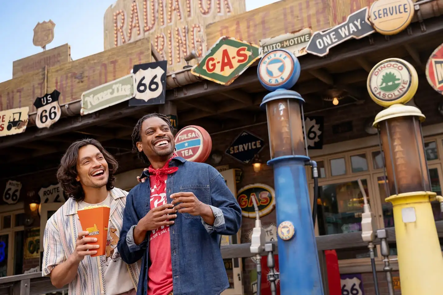 Two men smiling in front of Radiator Springs Curios Shop in Cars Land at Disney California Adventure.