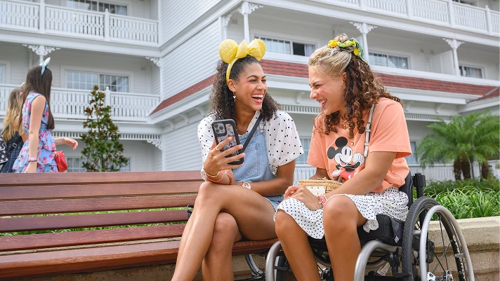 Two women laughing while looking at a phone.